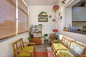 A cozy room with wicker furniture, a potted plant, a wall-mounted shelf, and a decorative hot air balloon.