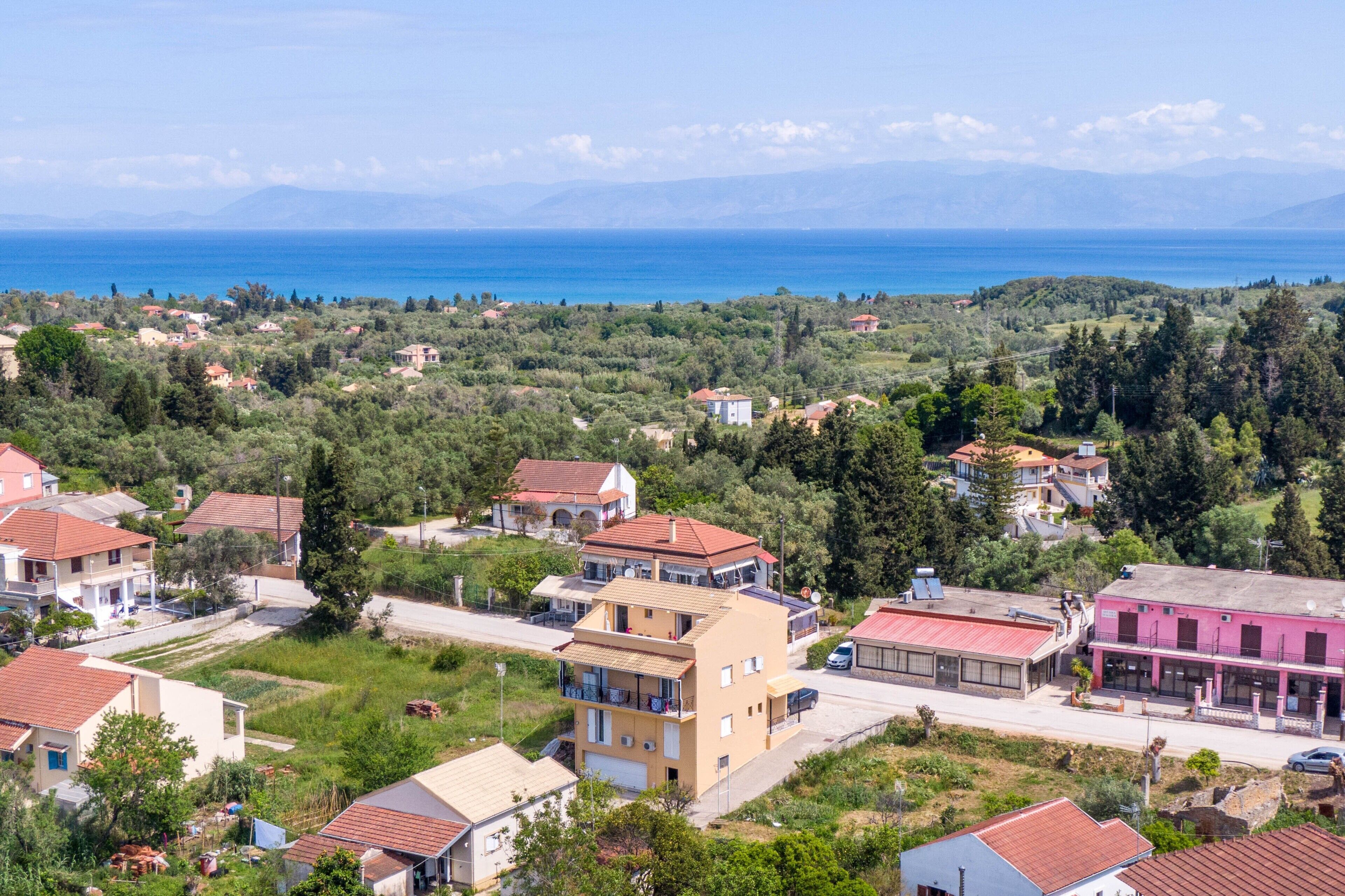 A coastal town with houses, a road, and a view of the sea.