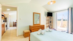 Une chambre à coucher avec un lit, une commode, un miroir, une télévision et une vue sur l’extérieur.