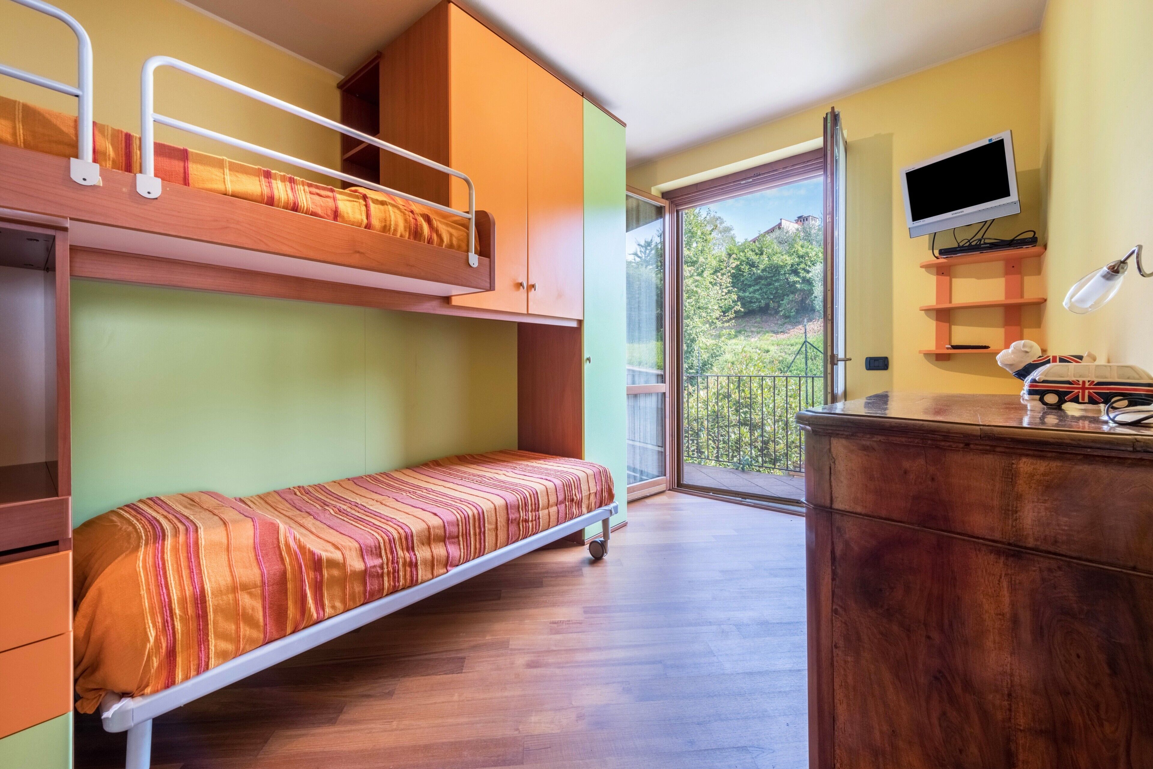 Una habitación con literas, un escritorio con lámpara, televisión y vistas a zonas verdes.