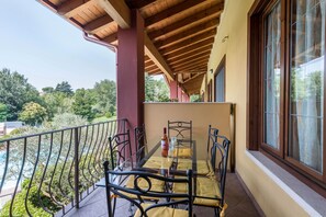 A balcony with a glass table, metal chairs, and a bottle.