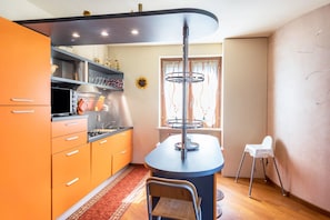 Une cuisine avec des meubles de couleur orange, un îlot central et une chaise blanche.