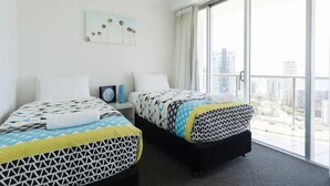 A hotel room with two beds, a large window, and a city view.