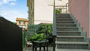 A narrow outdoor space with a table and chairs, a staircase, and a building in the background. - Holiday Home 'Pullin' with Private Garden and Wi-Fi (Carasco)