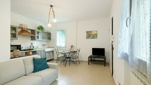 A compact living space with a kitchenette, dining area, and a TV. - Holiday Home 'Pullin' with Private Garden and Wi-Fi (Carasco)