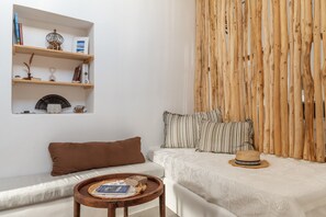 A room with a bed, a sofa, a wooden wall, and a shelf with books and decorative items. - Studio Apartment "Lithos" with Private Terrace & Wi-Fi (?a???)
