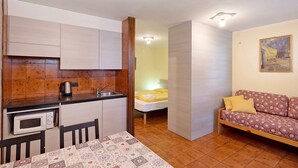 Une pièce compacte comprenant un coin cuisine, un lit, un canapé et une table.