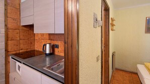 Une cuisine avec des meubles en bois, un évier en acier inoxydable et une bouilloire.