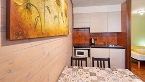 Une cuisine de taille réduite, équipée d’un four à micro-ondes, d’un évier et de meubles de rangement en bois.
