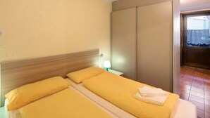 Une chambre d’hôtel avec un lit, une table de chevet avec une lampe, une armoire et une salle de bain visible à travers une porte ouverte.