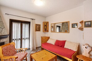 Une pièce comprenant un canapé, une table en bois, une chaise, un miroir et une cheminée.