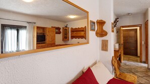 A room with a large mirror, wooden furniture, and a tiled floor.