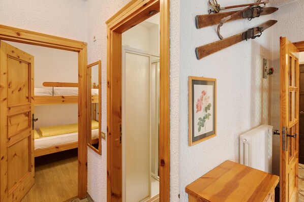 Une chambre avec un lit superposé en bois, une table en bois et un tableau encadré accroché au mur.