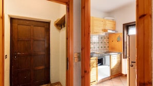 A wooden door, a kitchen with wooden cabinets, and a tiled backsplash.