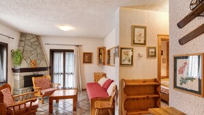 A cozy room with a fireplace, wooden furniture, and framed pictures on the walls.