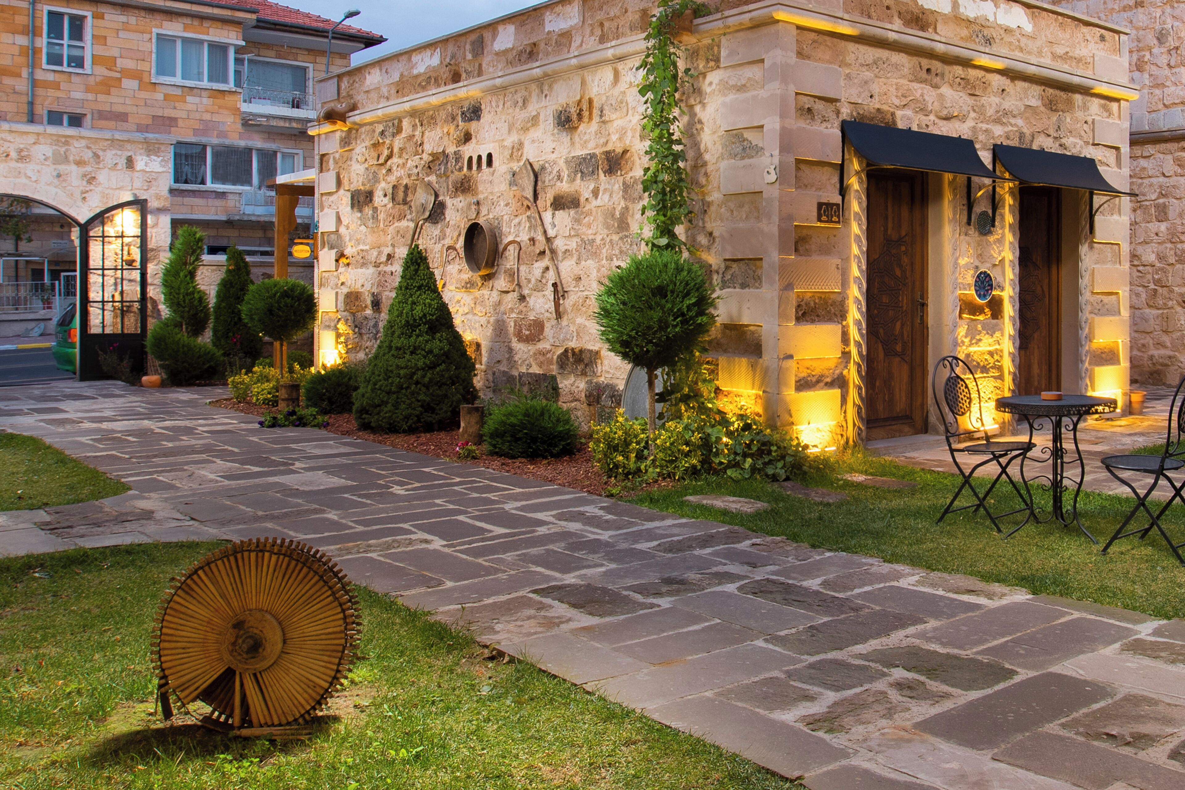A stone building with a paved walkway, outdoor seating, and a well-lit entrance.