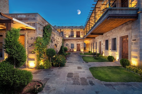 A courtyard with stone pathways, a wooden pergola, and a moon in the sky.