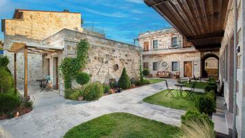 Un patio con muros de piedra, una pérgola y mobiliario exterior.