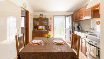 Comedor con una mesa dispuesta para dos, cocina con electrodomésticos modernos y vista a través de una puerta.