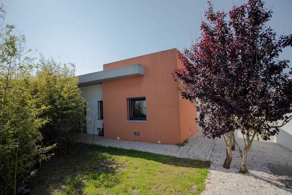 Un edificio moderno con tetto piatto, ingresso pavimentato e una piccola finestra.
