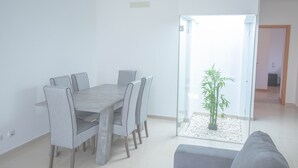 Ein modernes Wohnzimmer mit Essbereich, einer Glastür zum Balkon und einem grauen Sofa.