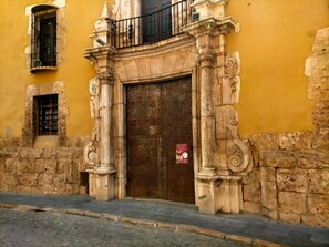 A historic building with a large wooden door, stone columns, and a small balcony with a black railing. - Vacation Home "Ca Josep" with Private Terrace, Balcony & Wi-Fi (Segorbe)