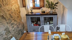 A wooden dining table with chairs, a tray with a teapot and cups, a cabinet with dishes, and a window with curtains. - Vacation Home "Ca Josep" with Private Terrace, Balcony & Wi-Fi (Segorbe)