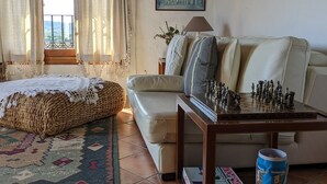 A cozy room with a bed, a sofa, a chessboard, and a painting on the wall. - Vacation Home "Ca Josep" with Private Terrace, Balcony & Wi-Fi (Segorbe)