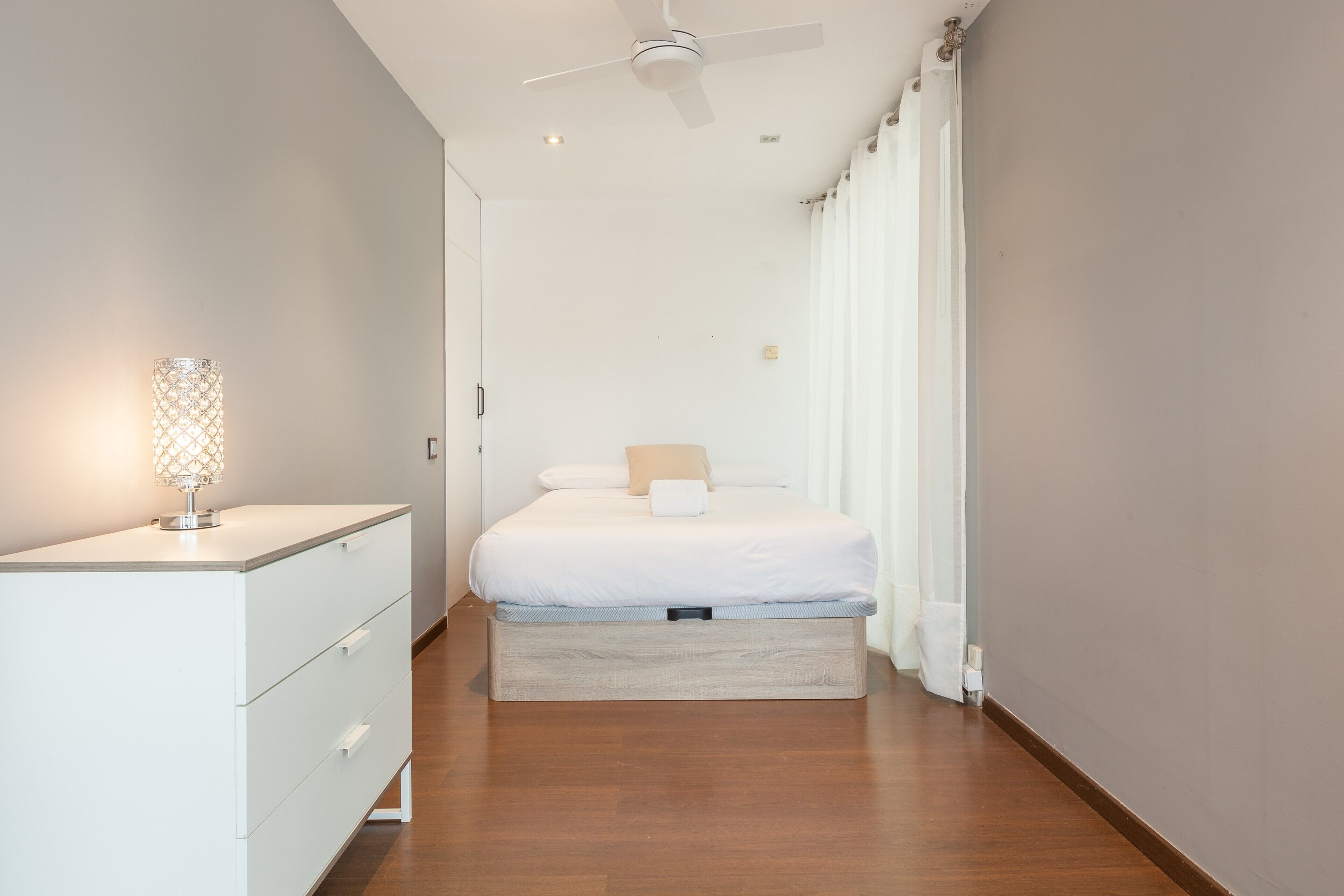 Ein Schlafzimmer mit einem Bett, einem Schminktisch, einem Deckenventilator und einem Nachttisch mit Lampe.