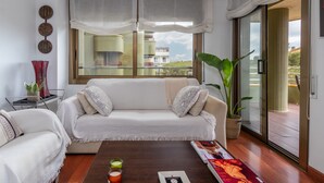 A modern living room with a sofa, a coffee table, a potted plant, and a view of the outside. - Maria Beach Apartment with Sea View, Wi-Fi, and Air Conditioning (castell-Platja d´Aro)