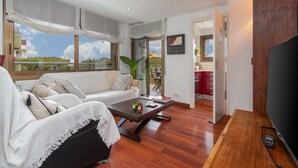 A modern living room with a sofa, coffee table, and TV. - Maria Beach Apartment with Sea View, Wi-Fi, and Air Conditioning (castell-Platja d´Aro)