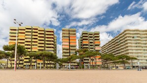 A beachfront hotel with multiple balconies, a sandy beach, and trees. - Maria Beach Apartment with Sea View, Wi-Fi, and Air Conditioning (castell-Platja d´Aro)