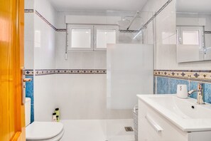 A bathroom with a white sink, mirror, and shower.
