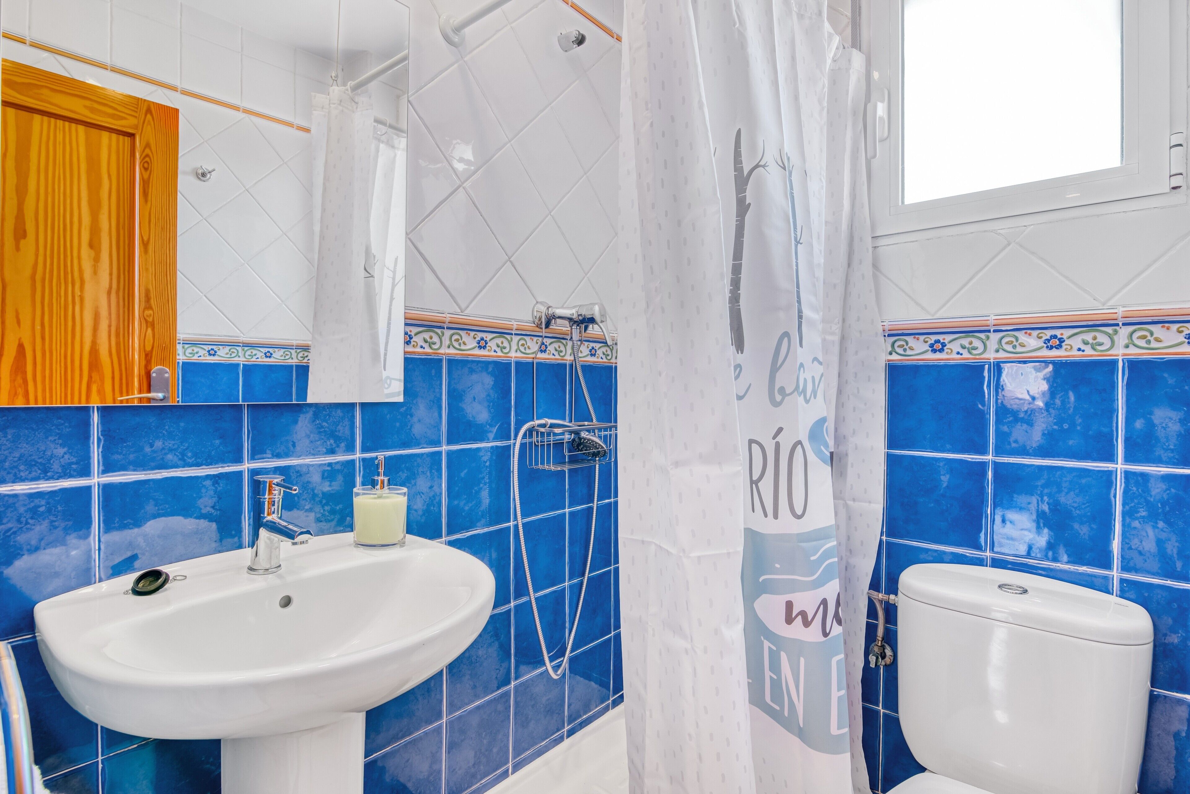 Un baño con un lavamanos blanco, una ducha con cortina y un inodoro.