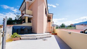 A two-story residential building with a balcony, outdoor seating, and a staircase leading to the upper floor. - Holiday Home "Casa Michela" with 2 Balconies and Wi-Fi (Orosei)