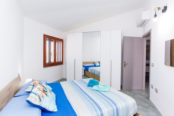 Une chambre à coucher avec un lit, une armoire, un miroir et une fenêtre avec des stores.