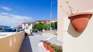 A narrow pathway leading to a building with a red-tiled roof, a white wall with a flower planter, and a street lamp. - Holiday Home "Casa Michela" with 2 Balconies and Wi-Fi (Orosei)