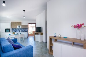 Un salon moderne avec un canapé bleu, une table basse en bois et un téléviseur en arrière-plan.