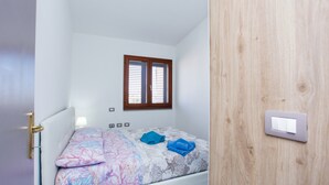 A bedroom with a bed, a window, a wall switch, and a door. - Holiday Home "Casa Michela" with 2 Balconies and Wi-Fi (Orosei)