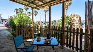 A covered outdoor seating area with a table, chairs, and a stone wall.