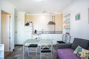 Une cuisine compacte comprenant une table à manger, des chaises, un canapé et un coin cuisine.