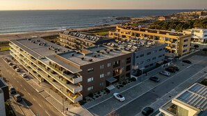Un hotel de varios pisos con aparcamiento en la azotea, vistas a la playa y una carretera costera.
