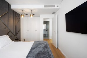 Une chambre à coucher moderne avec un lit, une armoire et un téléviseur fixé au mur.