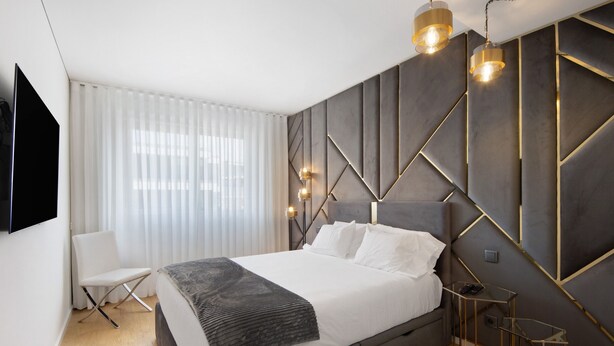 Un dormitorio moderno con cama, una silla, un televisor y un diseño de pared único.