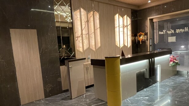 Un moderno vestíbulo de hotel con piso de mármol, paneles de techo de madera y una recepción.
