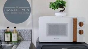 A kitchen with a microwave, a potted plant, and bottles of dish soap. - Inspiria Fully-Furnished Studio Unit with Balcony (Davao City)