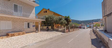 A street with a building that has a balcony and a stone-paved area.