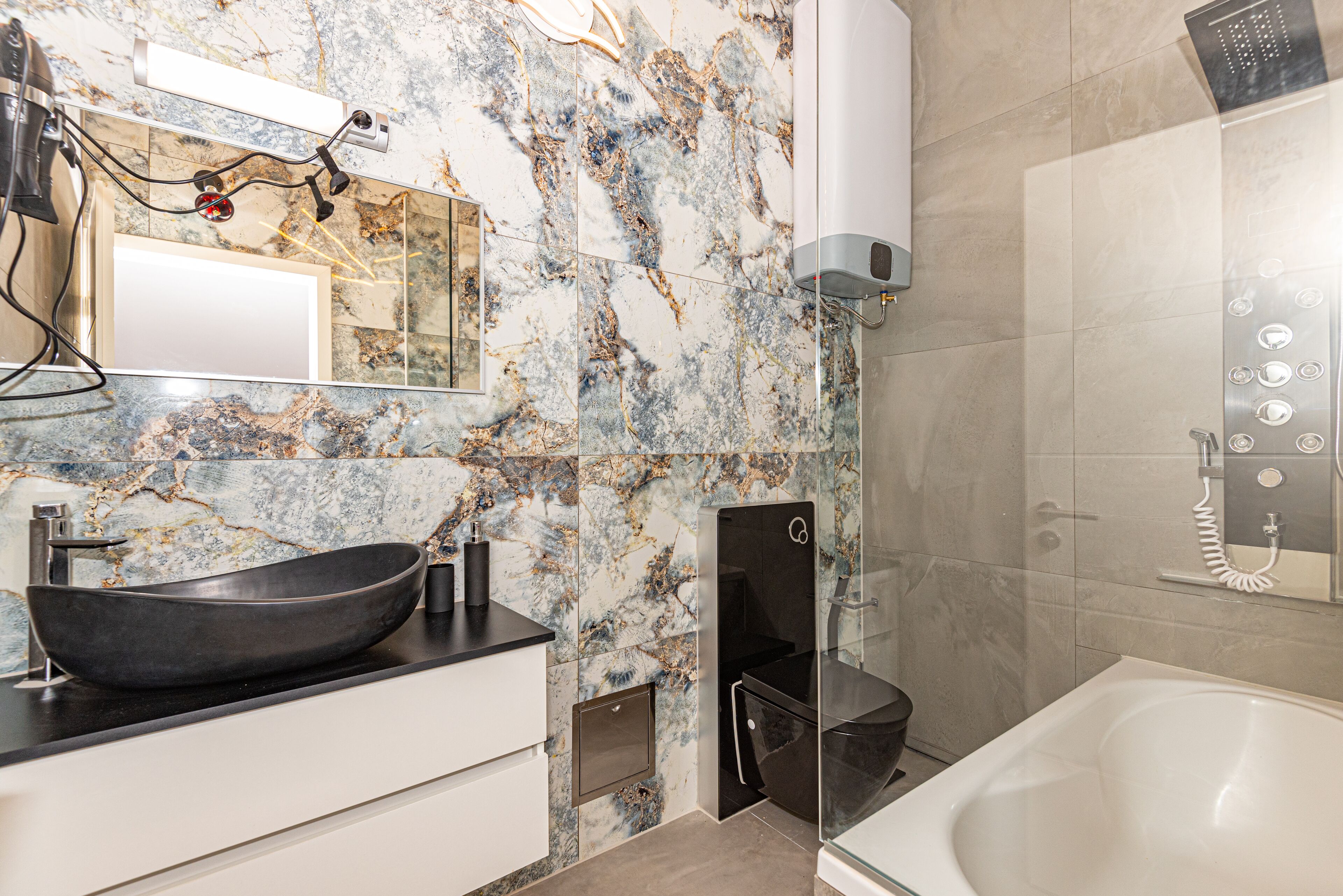 A modern bathroom with a black vessel sink, a glass shower enclosure, and a white bathtub.