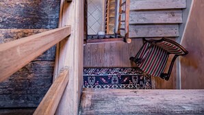 A wooden spiral staircase with a handrail and a patterned carpet at the bottom.