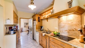 A kitchen with wooden cabinets, a granite countertop, a built-in stove, and a hanging light fixture.